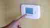 Person Pressing A Screen On A Thermostat